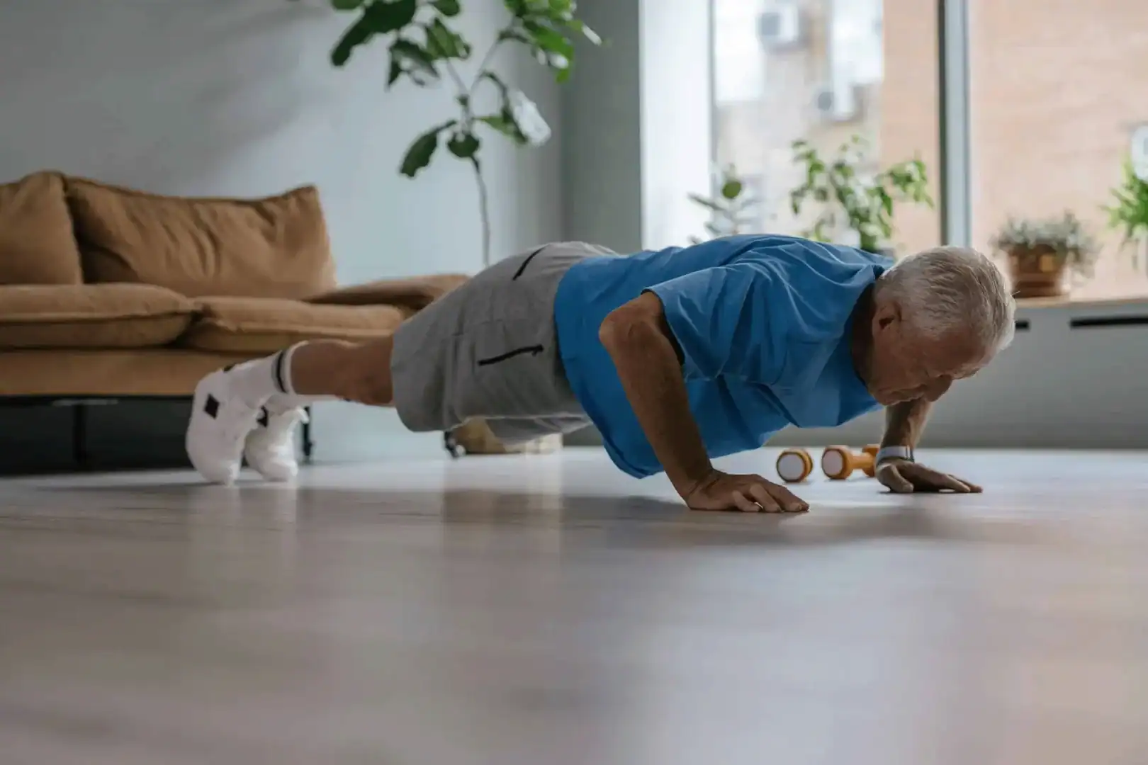 Uomo anziano che fa push-up a casa, attività fisica per un invecchiamento sano